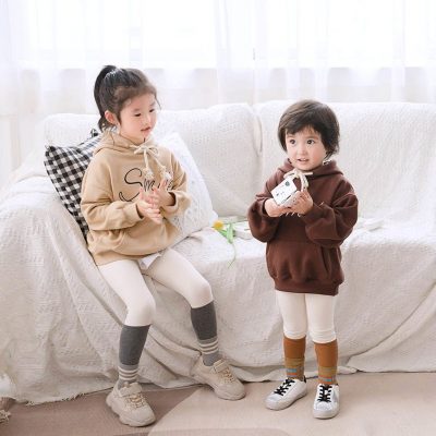 A couple of kids sitting on a couch playing with a cat Description automatically generated with low confidence